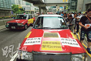 七月六日,香港的士司機發起慢駛,遊行的士貼上標語,促請政府打擊召車App涉非法載客。