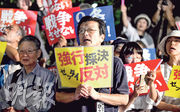 昨晚在東京出席反對新安保法案的民眾手持標語叫口號。（法新社）