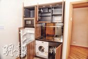 開放式廚房以啡色為主色調，並配備基本家電，包括抽油煙機、電磁爐、雪櫃等。