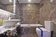 浴室以天然石鋪砌，洗手盆櫃提供儲物空間，方便收納物品。