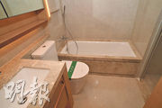 主人浴室設有浴缸，地面牆身以石材鋪砌，配備法國品牌潔具。（攝影：劉焌陶）