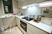 廚房以白色為主調，設有曲尺工作枱，及上下兩組廚櫃，整體空間光潔明亮。（楊柏賢攝）