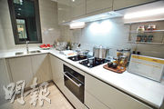 廚房以白色為主調，設有曲尺工作台，及上下兩組廚櫃，整體空間光潔明亮。（楊柏賢攝）
