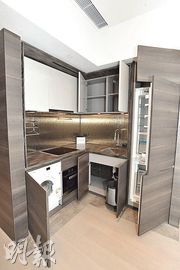 2房示範單位採開放式廚房設計，以棕色為主調，設廚櫃，配備電磁爐等。（劉焌陶攝）
