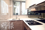 廚房家電齊全，設曲尺形工作枱，配有木色和白色廚櫃，儲物空間充足。（賴俊傑攝）