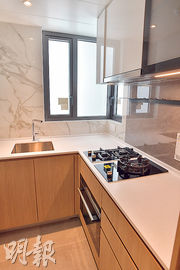 28樓C室交樓標準示範單位以木系廚櫃為主，附有雙門雪櫃、煮食爐、洗衣乾衣機等家電。