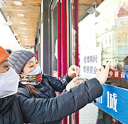 中國深陷新冠變種病毒擴散困擾，11月零售遜預期。圖為哈爾濱市中央大街，工作人員給商戶貼上「疫情期間 暫停營業」告示。（新華社）