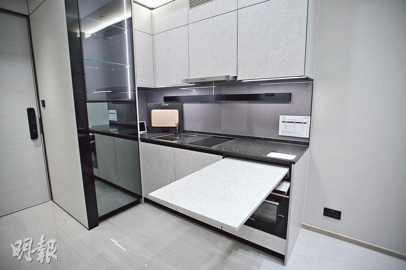 開放式廚房選用灰白色櫥櫃面板、配黑色金屬邊框，附有摺疊餐枱。