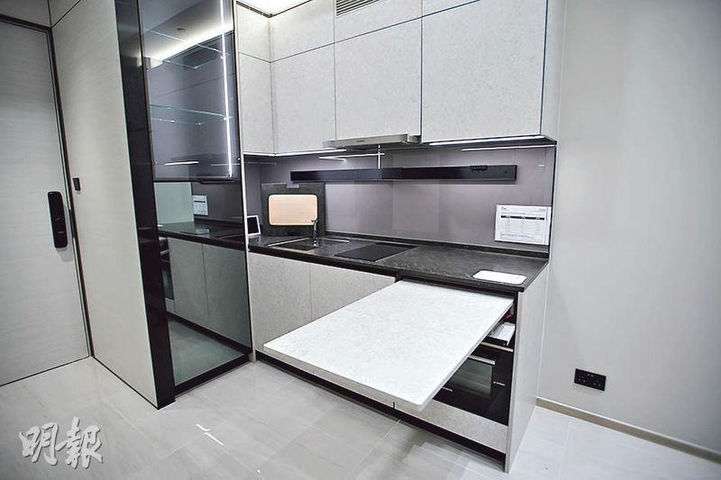 開放式廚房選用灰白色櫥櫃面板、配黑色金屬邊框，附有摺疊餐枱。（楊柏賢攝）