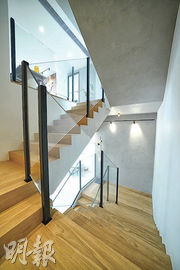 客廳通往1樓的樓梯，選用橡木地板及水泥外牆，加上玻璃扶手，增添舒適感。（黃志東攝）