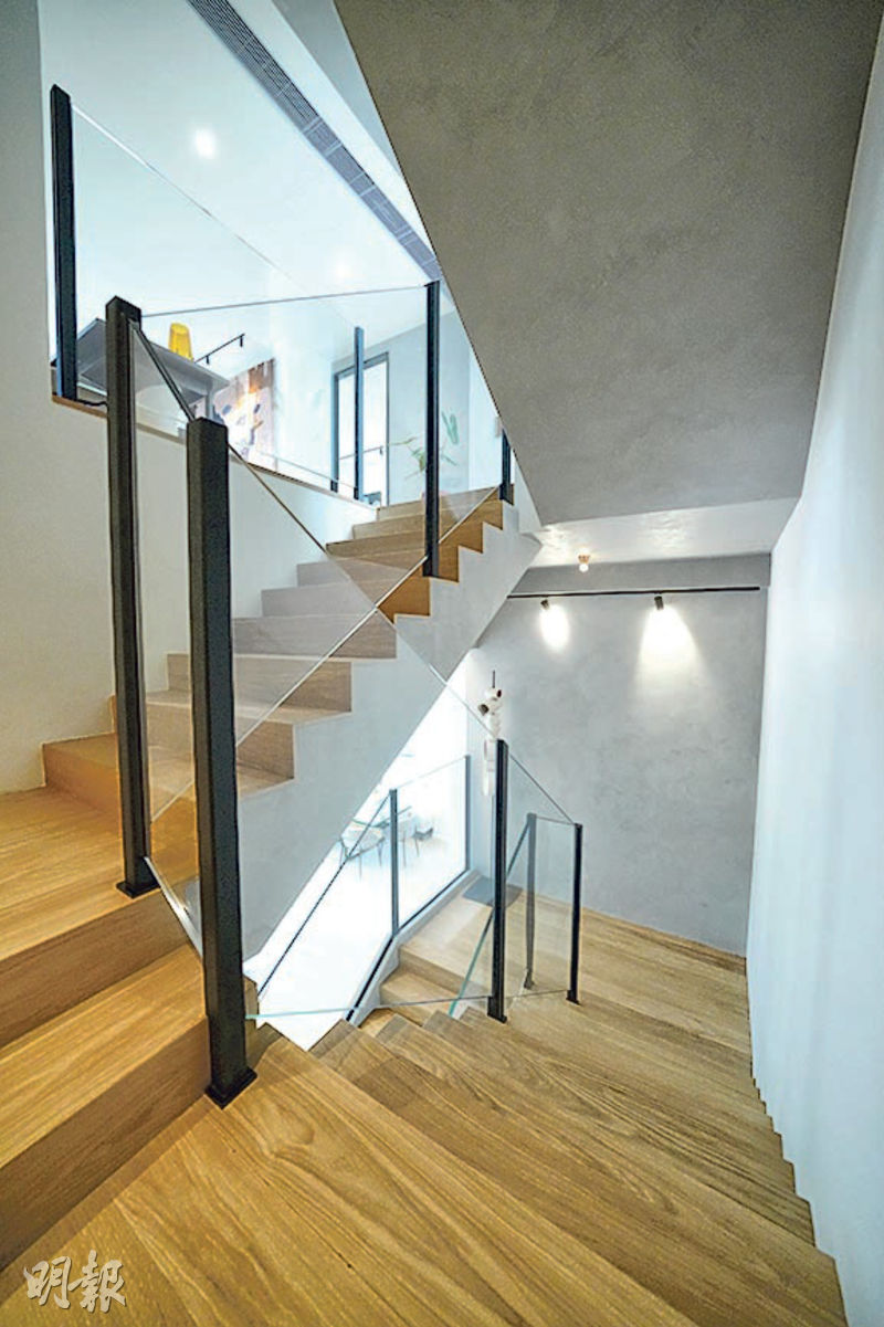 客廳通往1樓的樓梯，選用橡木地板及水泥外牆，加上玻璃扶手，增添舒適感。（黃志東攝）