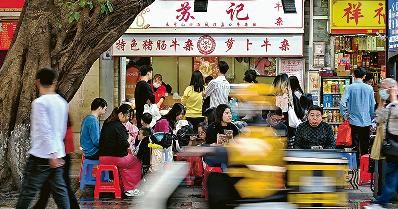 圖為廣州民眾在北京路步行街品嘗美食。內地12月份社會零售品零售總額按年增長7.4%，低於市場預期的8%，不過餐飲消費受惠疫後解封，增速按年加快至30%，成為支持經濟增長一大動力。（中新社）