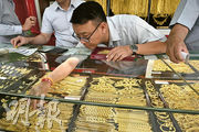 圖為曼谷的金行職員向顧客展示金飾。美國股匯債受壓，促使資金流入黃金避險，現貨金首次升穿每盎司3200美元關口。（法新社）