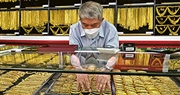 投資市場避險持續升溫，觸發資金流入金市，國際金價昨日首度衝上3500美元大關，曾見3509美元的歷史新高。圖為泰國曼谷唐人街一間金舖店員正在處理黃金首飾。（法新社）