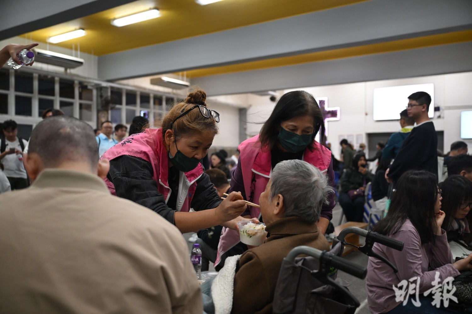 中華基督教會馮梁傑紀念中學禮堂內關愛隊協助在場行動不便長者進食。(鍾林枝攝)