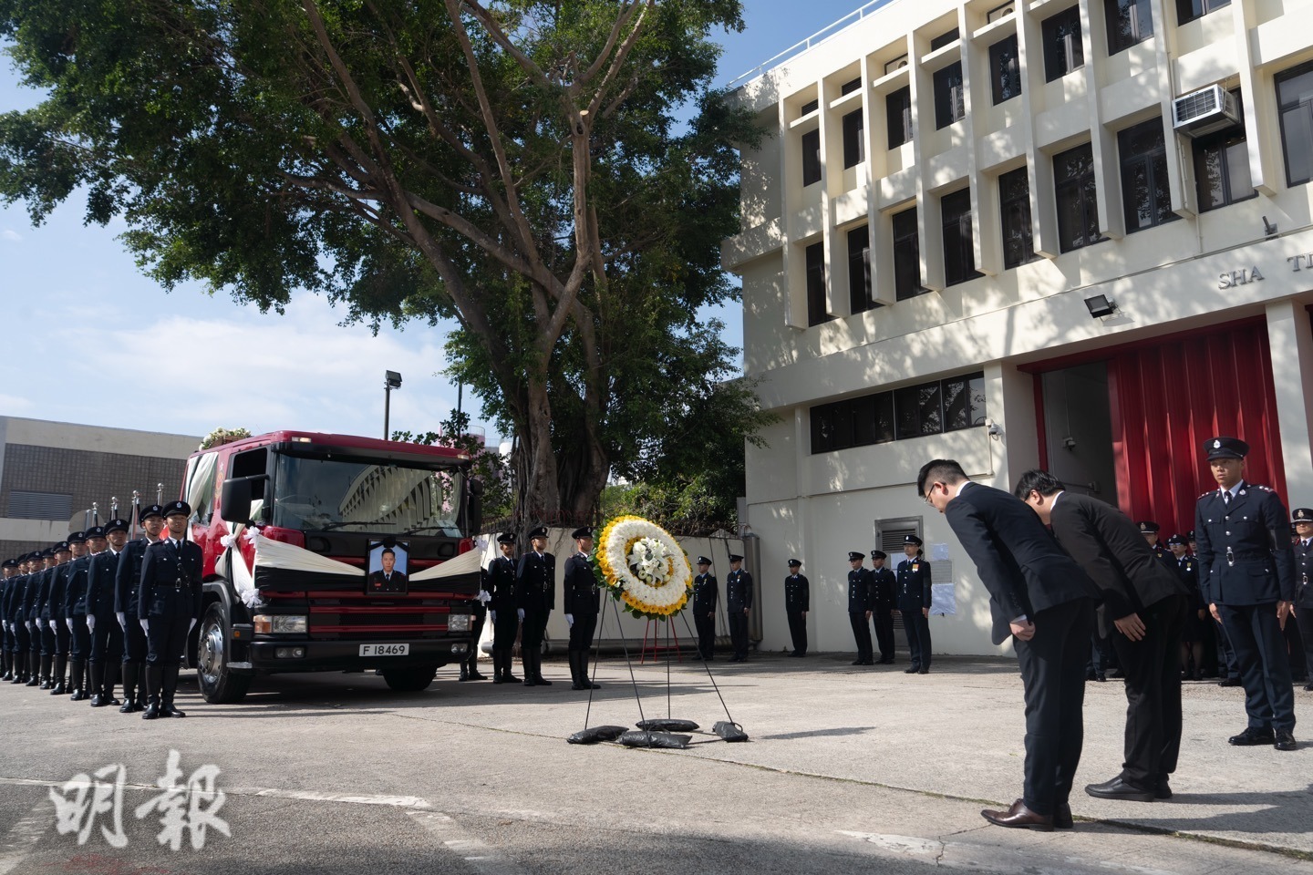 靈車上午約11時40分到達沙田消防局，在場人士鞠躬致敬。（徐君浩攝）