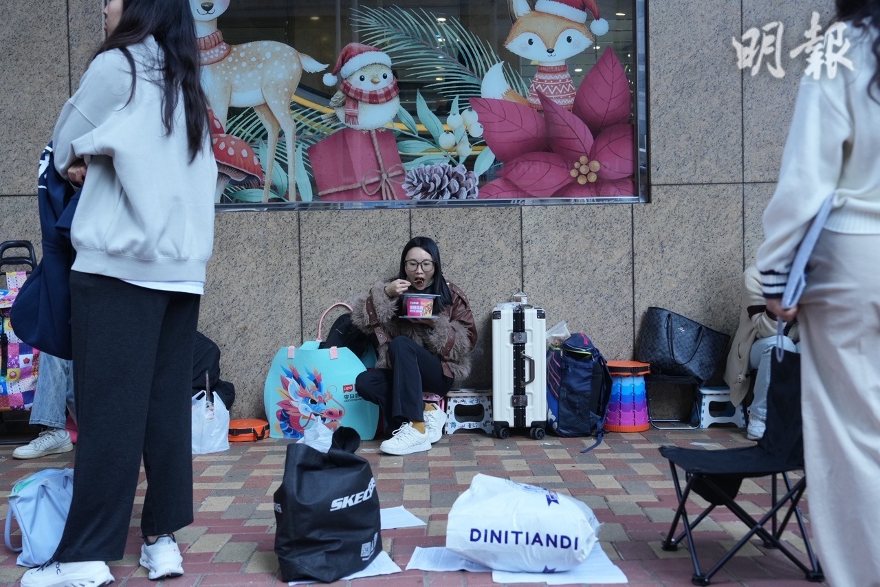 有人攜折疊凳、行李箱及即食食品在金鐘牌照事務處外排隊。（楊柏賢攝）