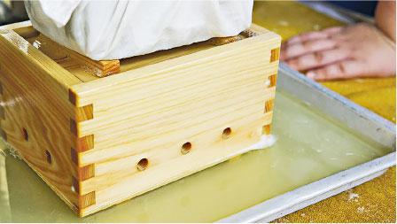 排出水分——在模具頂部放置磚頭，並以持久及均勻的力度向豆腐施壓，可令多餘水分透過小孔排出。（生活Kids Club提供）