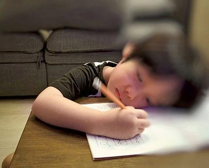 肌張力低的孩子，常常伏在桌上做功課。（模擬照片，受訪者提供）