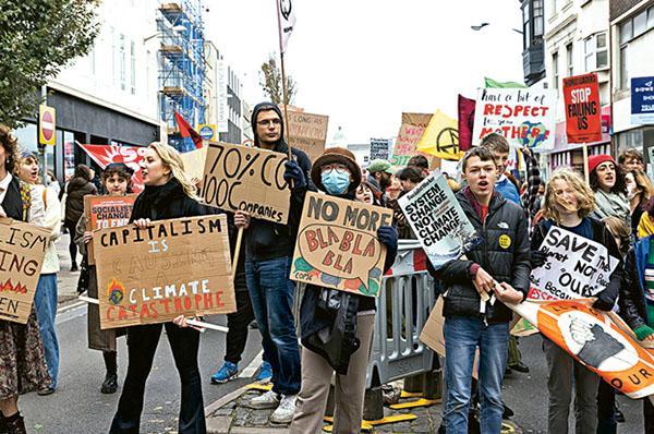 趁第26屆聯合國氣候峰會（COP26）舉行期間，不少環保人士遊行抗議各國領袖行動不夠積極，Lance（中）也參與其中。（受訪者提供）