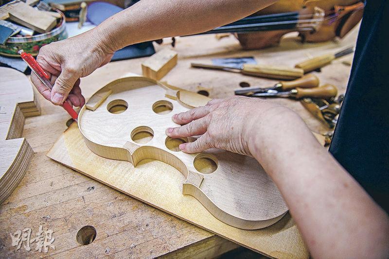 畫形狀——製琴第一步是在木材上畫出小提琴形狀，以便切割。雖然有固定式樣可以依循，但外觀線條做得是否流麗就要看琴匠手藝，黃煒權表示外觀線條也會影響音色是否甜美。（賴俊傑攝）