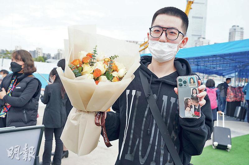 在深圳灣關口，米先生手持花束等候女友，並向記者展示貼在手機背後的女友照片。他的女友在港讀書，二人一年多未見，會在深圳一起遊玩幾天。（林迎攝）