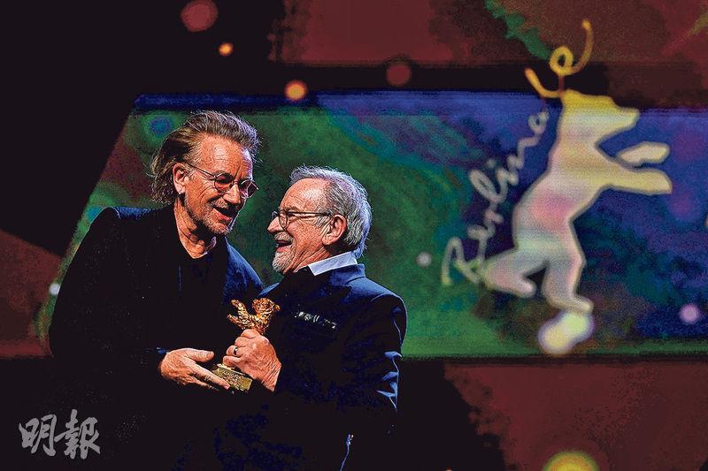 日前在柏林影展宣傳紀錄片《Kiss the Future》的Bono（左），驚喜擔任終身成就獎頒獎嘉賓，還稱很喜歡史匹堡（右）的電影。（法新社）