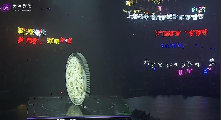 舞台中央有巨型的張國榮紀念幣。（《繼續寵愛‧二十年‧音樂會》視頻截圖）