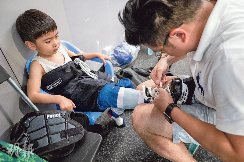 協助穿鞋——在香港冰球訓練學校的「冰球新世代」初階溜冰課程的學生，年紀最小的只有4歲，就連穿裝備時也要家長出手協助。（朱安妮攝）