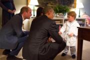 美國總統奧巴馬（中）蹲下跟喬治小王子（右）握手。（The British Monarchy facebook圖片)
