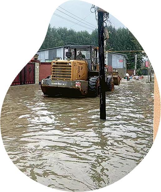 涿州一輛鏟車涉水前往救災，後方有一群徬徨無助的村民。（野草書店老闆趙亮提供）