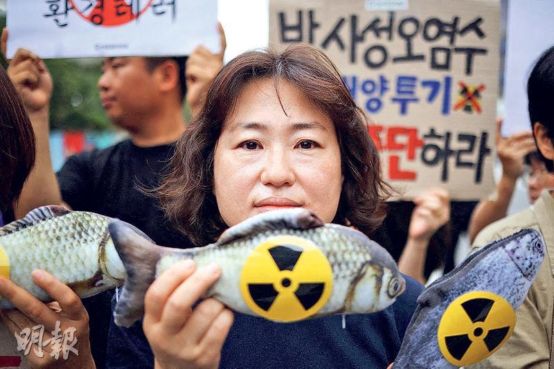 日本排放核污水入海，韓國首爾周五有示威者拿起貼有核輻射標誌的魚公仔抗議。（路透社）