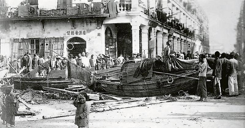 1906年丙午風災過後，有舢舨被吹至油麻地街頭，引來多名市民圍觀。（海事博物館圖片）