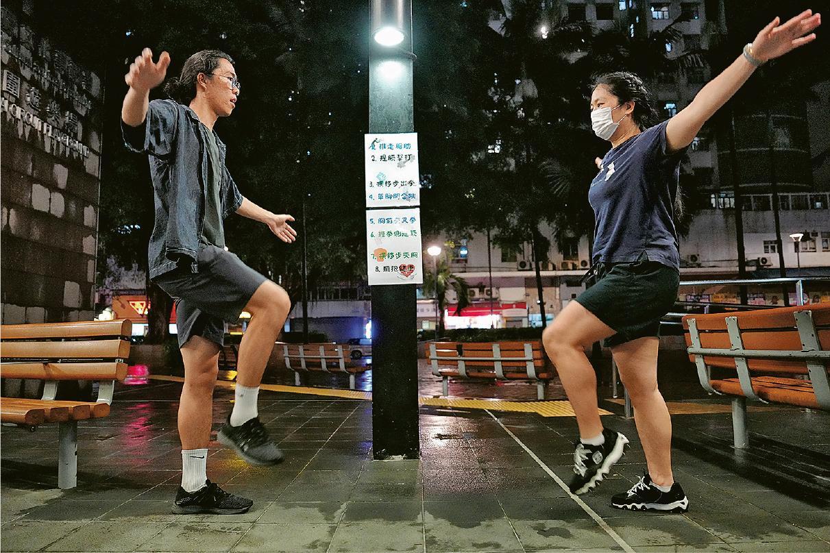 健體教練譚思哲（左）和家庭主婦紫虹（右）示範健康操八式之一：提膝擊打。（黃志東攝）