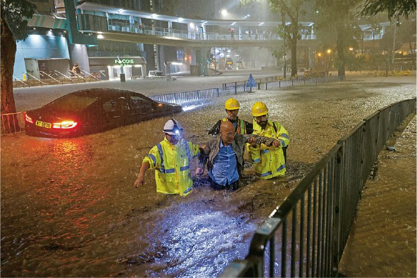 早前極端暴雨突襲香港，本港多區嚴重水浸。部分人滯留街上，需協助才能離開。（路透社）
