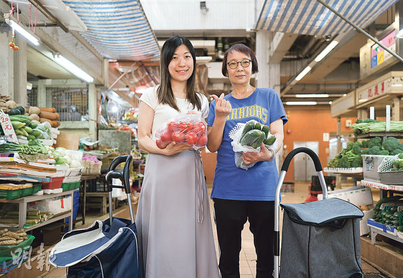 營養學家楊詩韻（左）與街坊瑞蓮（右）捧著從愛心商戶收集的蔬菜。（鄧家烜攝）
