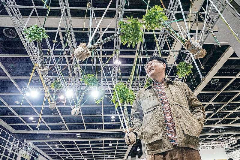 2023年Art Basel HK的裝置藝術項目「藝聚空間」，香港藝術家楊沛鏗（圖）展示裝置作品《屋簷下的擁抱先生們》（楊背後的作品）。2024年他將代表香港參與威尼斯國際雙年展。（資料圖片）