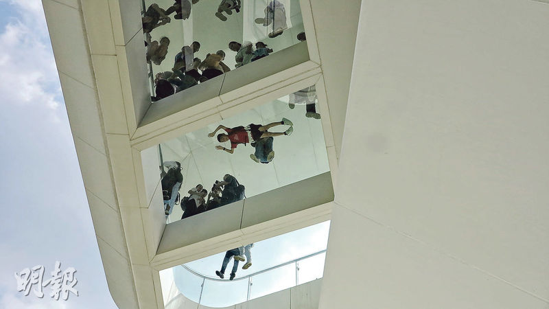 在2樓船頭甲板仰望第3層「全景玻璃眺望台」，有小童俯伏透明玻璃地板，跟樓下遊人打招呼。（蔡朗清攝）