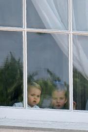 2019年6月8日，英女王伊利沙伯二世93歲官方壽辰閱兵巡遊慶祝活動在白金漢宮舉行，夏洛特小公主（左）和路易小王子（右）未出陽台前，在窗前好奇外望。（法新社）