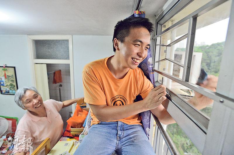 高大的阿進（右）自言愛清潔，在79歲獨居長者丁丁（左）家中抹窗，即使爬到上格牀曲起腳抹窗亦不覺辛苦，獲丁丁大讚。（鄧宗弘攝）