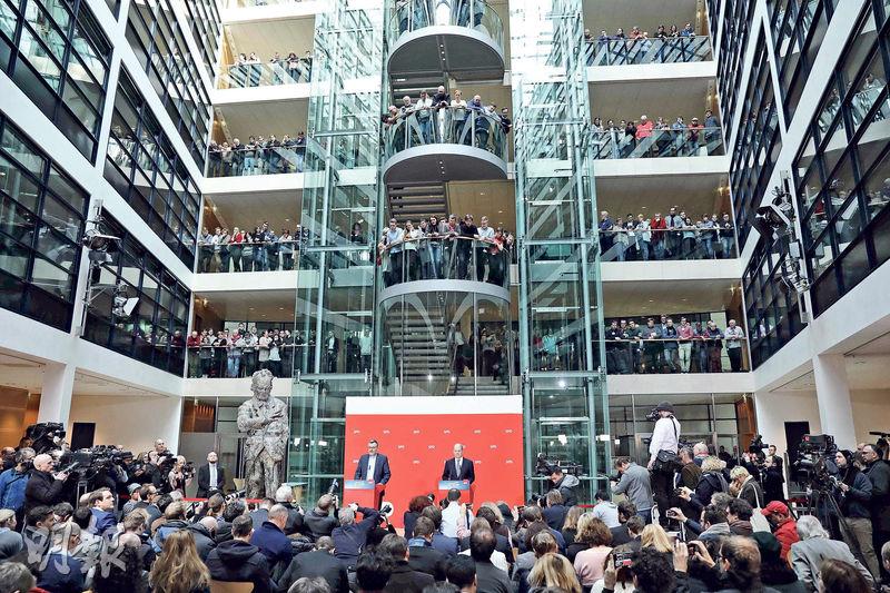 德國社民黨署理黨魁兼漢堡市長紹爾茨（右）昨在柏林總部聆聽黨司庫宣布表決結果，結果以66%贊成票通過再與基民盟／基社盟合組「左右大聯盟」。