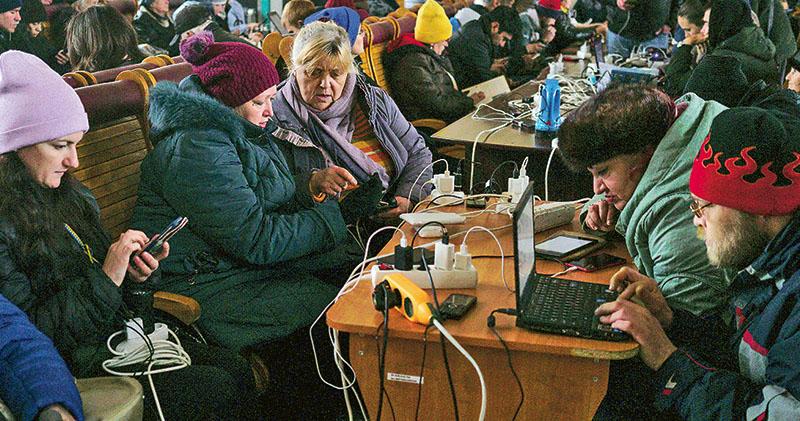 雖然俄軍已撤出烏克蘭南部重鎮赫爾松，但當地仍面對缺電問題，有民眾周二在火車站為手機等電子產品充電。（路透社）