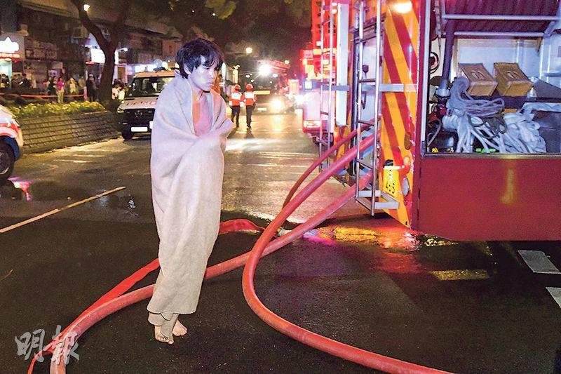 吸入濃煙不適的梁氏兄弟，弟披上毛氈自行登上救護車送院。（蔡方山攝）