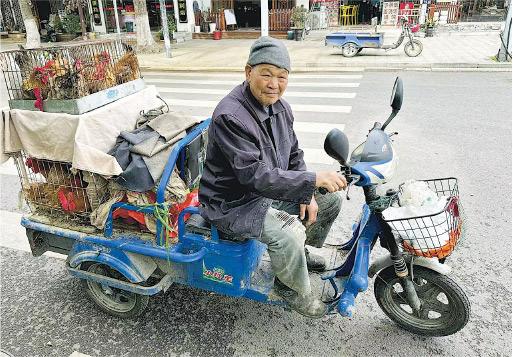 江玉歡話喺江蘇周莊見到一個販商開住架摩托車賣雞，話老人家樂在其中。佢想到香港，慨嘆「凡是難管難處理的，我們全部慢慢地將它們取締。小販、霓虹燈是否不得留下？」（江玉歡facebook圖片）