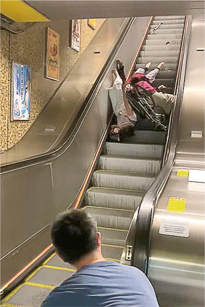 黃大仙地鐵站扶手電梯昨發生意外，涉事老婦及其中一名同行女子「倒豎葱」倒在扶手電梯上，另一名同行女子則跌坐在旁，一張已摺起的輪椅亦跌在附近，一支拐杖遺漏在上方梯級。（網上片段截圖）