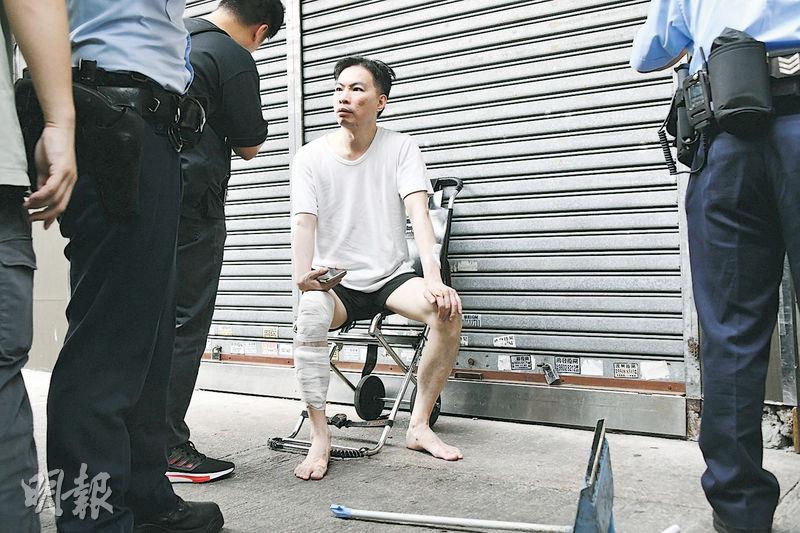 51歲陳姓本地男子赤腳逃出單位，左右手及右腳均有受傷，坐在路旁包紮，身旁有斷柄的垃圾鏟及掃把。（蔡方山攝）