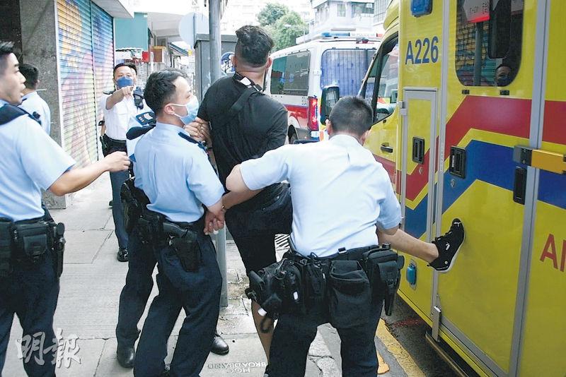 非華裔男被捕時情緒激動，一度用腳抵住救護車門，拒絕上車，又以粗口喝罵記者，其後被帶上警車。（蔡方山攝）