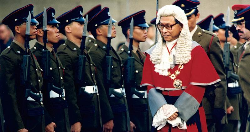 楊鐵樑於1988年獲英女王冊封為勳爵，同年晉升首席大法官，成為本港首名華人出任此職。圖為他於1995年新法律年開啟典禮上檢閱英軍儀仗隊。（資料圖片）