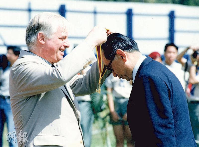楊鐵樑（右）多年來積極參與本港社會事務，曾任香港童軍總會會長。他於1992年獲時任港督彭定康（左）頒予金龍勳章，表揚其對童軍運動的貢獻。（資料圖片）
