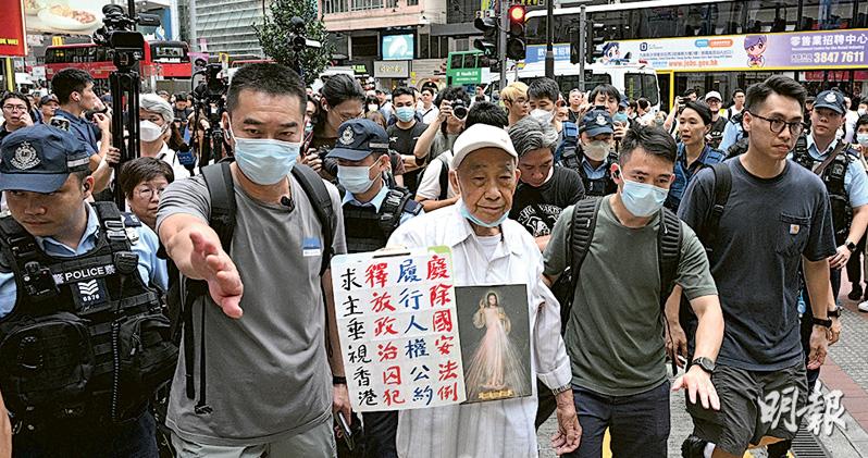 身掛耶穌圖樣的吳先生昨午在銅鑼灣崇光百貨外行走，手持寫上「廢除國安法例、釋放政治囚犯、履行人權公約、求主垂視香港」的紙張，不足5分鐘後遭警員截查，其後被警員由銅鑼灣站「護送」至油塘站自行離開。（曾憲宗攝）